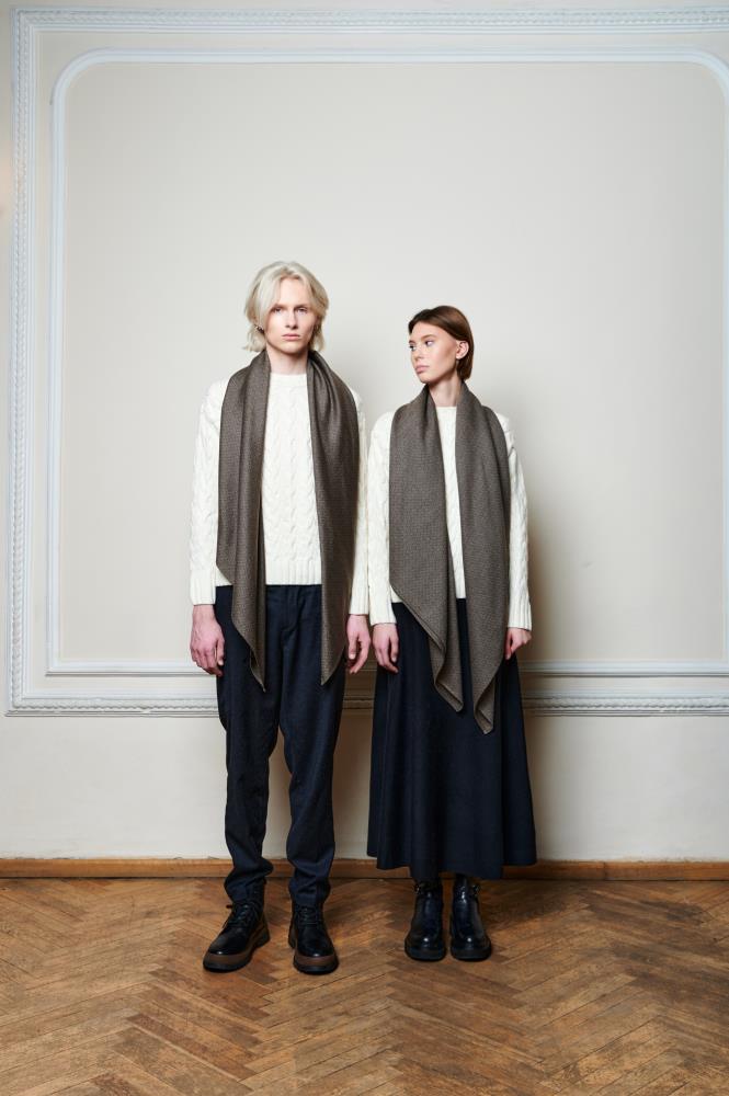 Two models, one male and one female, wearing beige and brown wool scarves of the SKARELE brand, standing against a plain background.