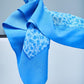 Close-up of a premium  blue silk scarf, showcasing the iconic logo, delicate floral print, and the soft, elegant drape of the high-quality fabric.