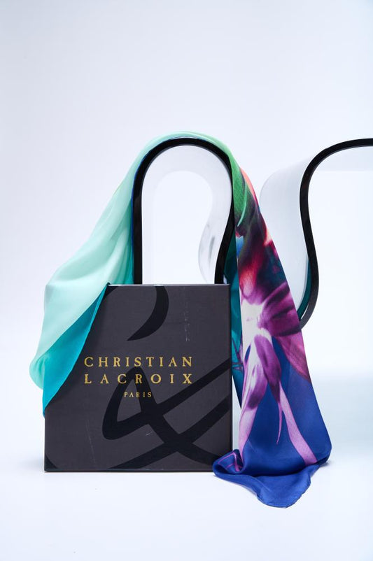 A multicolor bluish silk scarf with rolled and tucked edges, branded with 'Christian Lacroix', displayed in an authentic box with the brand name visible.