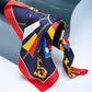 silk scarf with a nautical design featuring gold keys, chains, and maritime signal flags, elegantly draped over a curved glass surface in a minimalist studio.