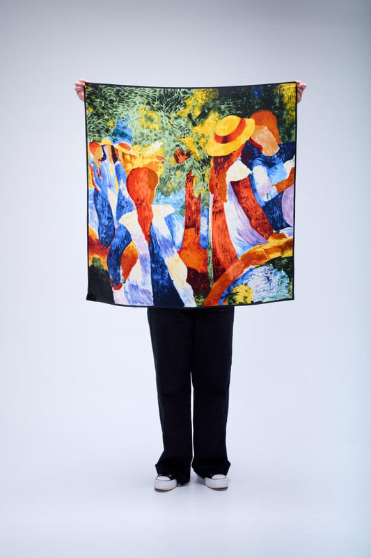 A person holding up a large square silk scarf featuring an impressionist-style painting of women in a garden, with vibrant brushstrokes in blue, orange, and yellow on a white studio background.