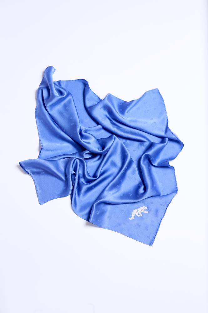 A light blue silk scarf with an embroidered 'Cartier' panther, displayed on a white background.