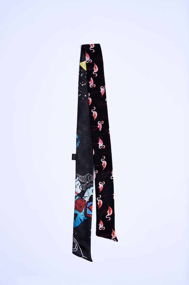 A narrow "Twilly" silk scarf with a double-sided design: one side features pink flamingos, while the other showcases colorful space and astronaut motifs on a black background. A modern and playful accessory that adds a unique touch to any look.