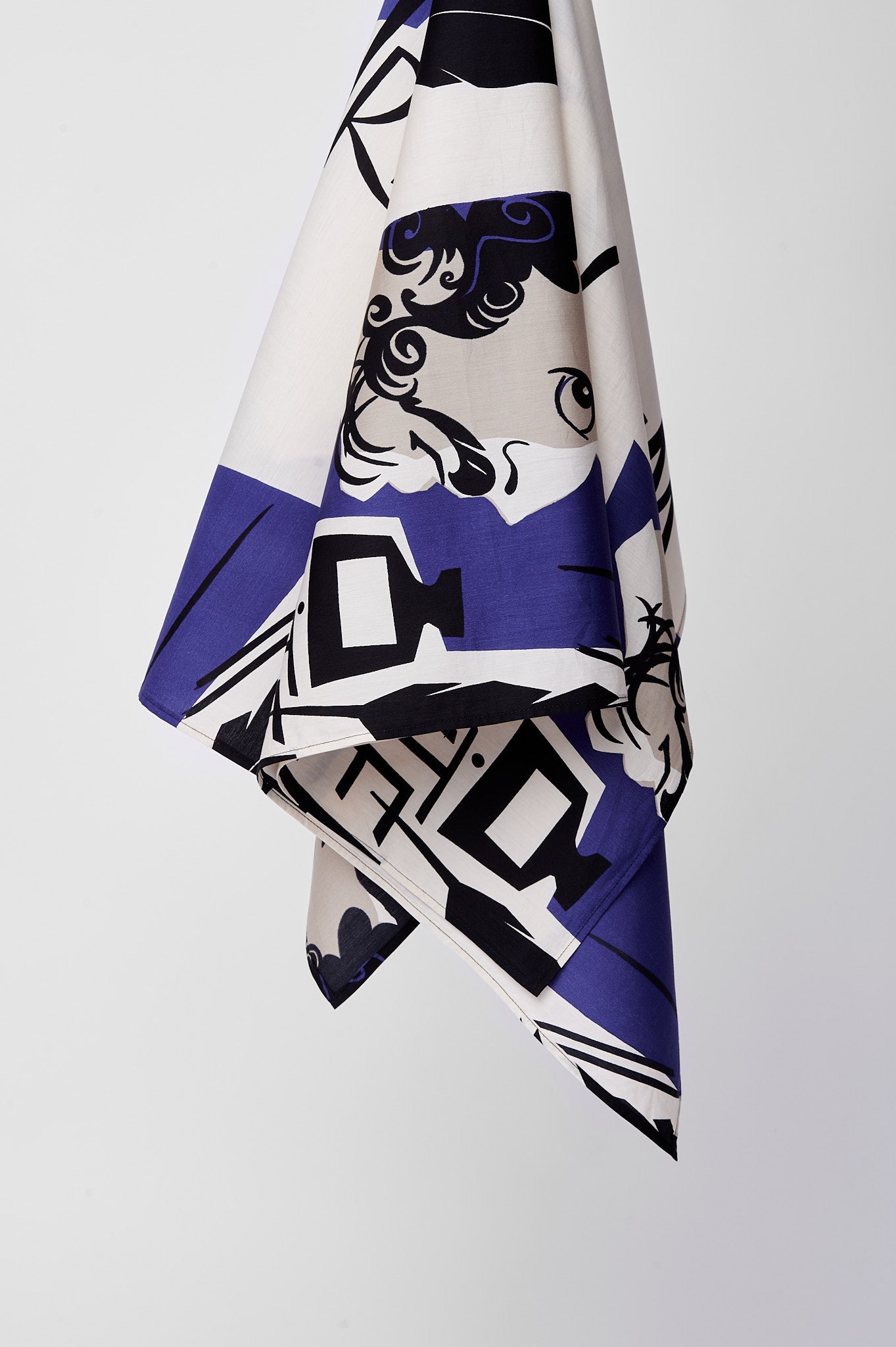 Hanging fabric with a bold design features blue and black patterns, including a stylized face. The clean composition conveys modern and artistic tones.