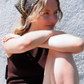 SKARELE "la dolce vita" brown bandana  with yellow and blue abstract dot pattern, worn by a young woman in bright sunlight against a textured wall