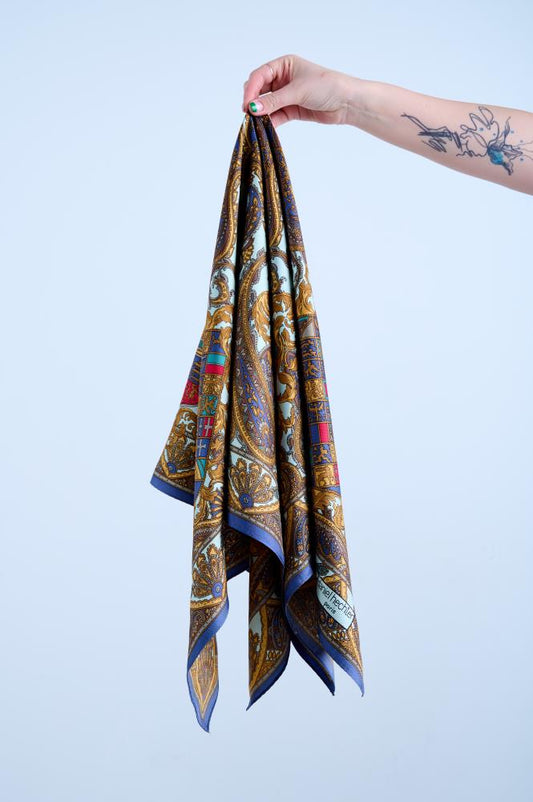 A multicolored silk scarf with a kaleidoscopic pattern, held up against a light background.
