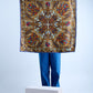 A person in blue jeans holding up a large square silk scarf featuring an intricate heraldic design with regal crests, ornate paisley patterns, and golden baroque details on a light blue and bronze background, finished with a navy blue border.