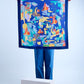 A person holding up a large square navy blue silk scarf featuring a vibrant, abstract underwater-themed print with colorful fish, coral-like shapes, and surreal elements in orange, yellow, and turquoise, framed by a dark blue border.