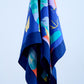 A vintage navy blue silk scarf featuring a vibrant abstract art print with colorful fish and coral motifs in orange, yellow, and turquoise, elegantly draped to showcase the fluid fabric