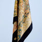 A high-quality silk scarf featuring a vibrant Impressionist-style painting print, with rich yellow, gold, and green tones, framed by a bold black jacquard border.