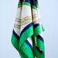 Close-up of a high-quality silk scarf with a nautical and equestrian theme, featuring golden chains and leather belts on a navy blue, white, and emerald green background.