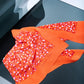 A bright orange silk scarf with violet and white dots, displayed on a flat surface.