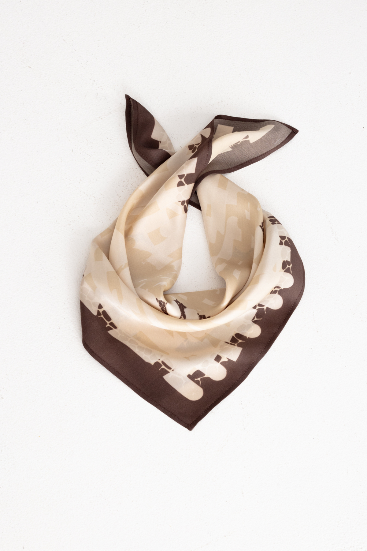 A square silk scarf with a beige and brown horse pattern, tied in a knot on a plain white background.