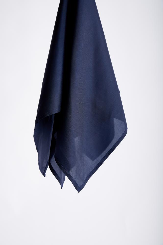 A dark blue silk scarf, partially transparent, hangs elegantly against a plain white background. The fabric drapes smoothly, creating a minimalist and serene tone.