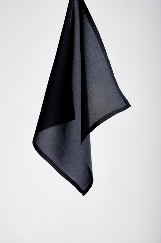 A single, suspended black cloth hangs against a plain gray background, conveying simplicity and elegance with its soft folds and flowing lines.