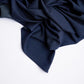 A dark blue wool scarf with small green details, laid out on a flat surface.