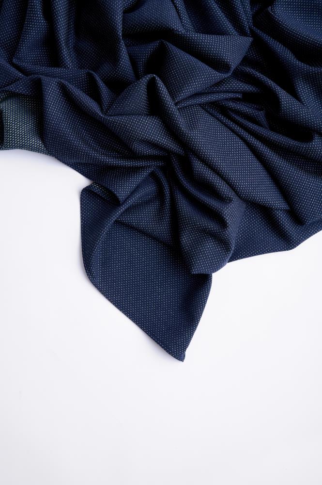 A dark blue wool scarf with small green details, laid out on a flat surface.