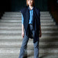 Person standing on a set of stairs wearing a blue wool scarf, denim shirt, and gray jeans