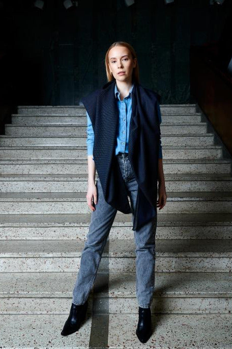 Person standing on a set of stairs wearing a blue wool scarf, denim shirt, and gray jeans